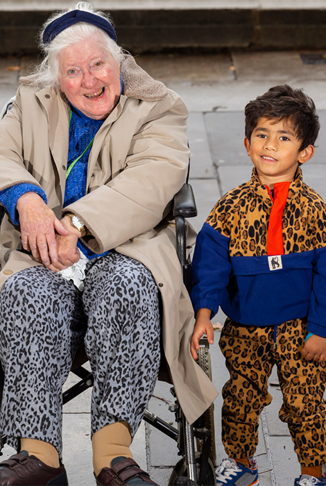 Old lady in a wheelchair and a 5 year old boy smilig at the camera
